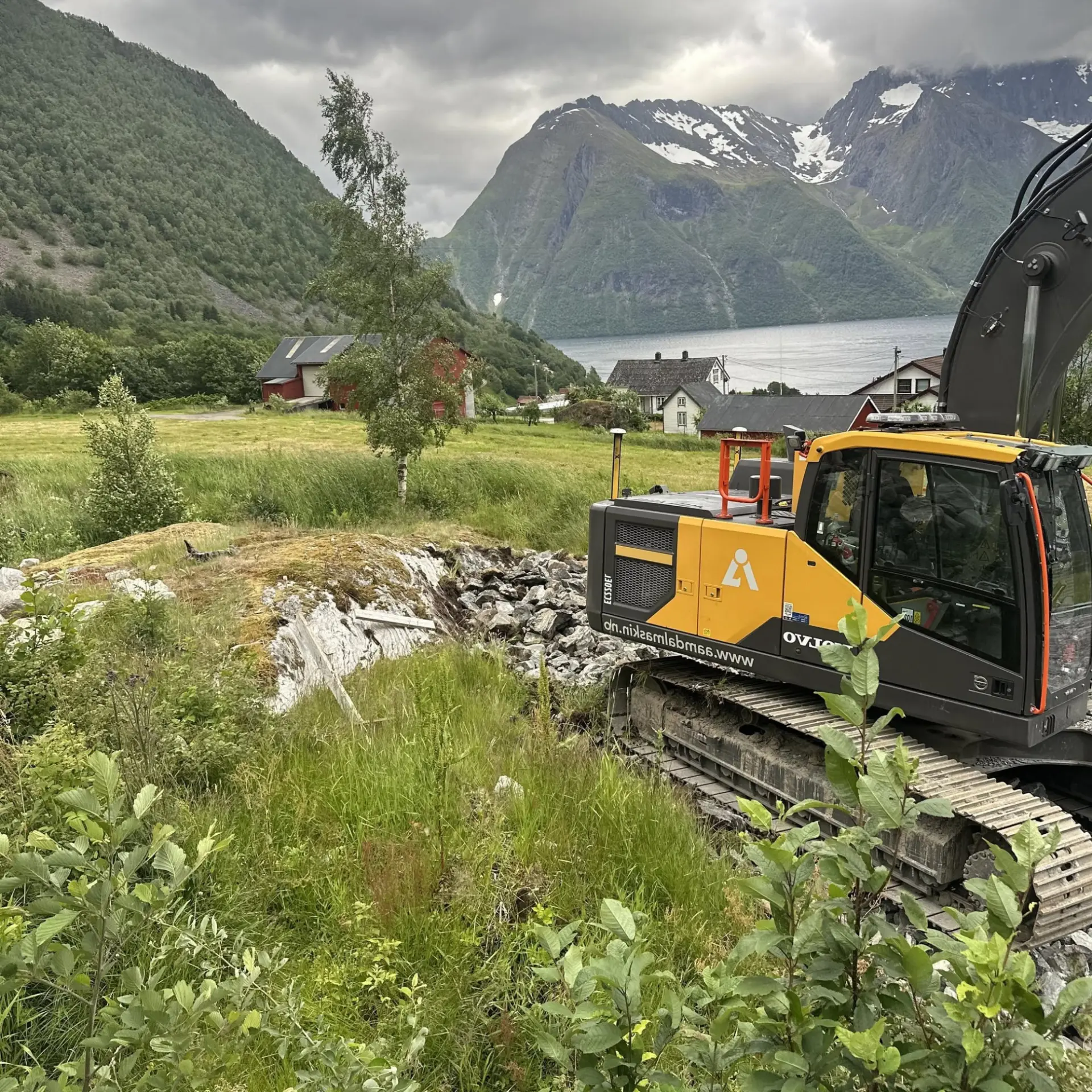 Volvo gravemaskin frå Åmdal Maskin med utsikt over fjord og fjell på Sunnmøre